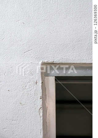 A corner of a white textured wall with a metal doorway frame A corner of a white textured wall with a metal doorway frame 126369300