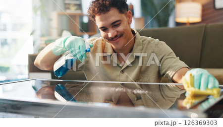 Happy man, spray bottle and table with detergent for housekeeping or cleaning service at home. Male person, maid or cleaner with smile, gloves or cloth for bacteria or germ removal on glass surface 126369303