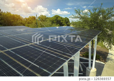 Aerial view of solar panels installed as shade roof over parking lot for parked cars for effective generation of clean electricity. Photovoltaic technology integrated in urban infrastructure Aerial view of solar panels installed as shade roof over parking lot for parked cars for effective generation of clean electricity. Photovoltaic technology integrated in urban infrastructure 126369357