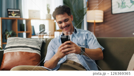 Relax, smile and man on smartphone on sofa for communication, chat or reading message. Home, online and happy person on internet for texting, social media and browsing website to download application 126369365