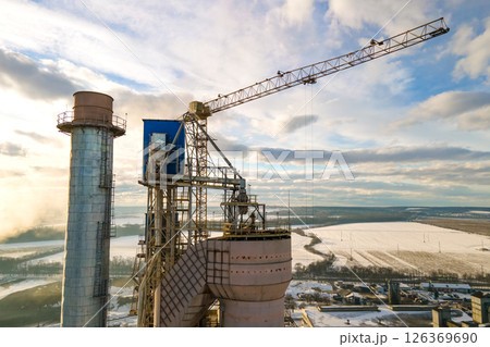 Aerial view of cement plant with high factory structure and tower crane at industrial production area at sunset. Aerial view of cement plant with high factory structure and tower crane at industrial production area at sunset. 126369690