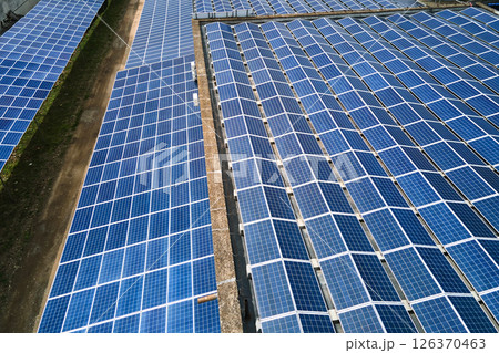 Aerial view of blue photovoltaic solar panels mounted on industrial building roof for producing green ecological electricity. Production of sustainable energy concept. Aerial view of blue photovoltaic solar panels mounted on industrial building roof for producing green ecological electricity. Production of sustainable energy concept. 126370463
