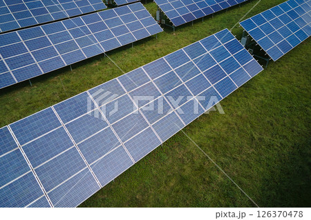 Aerial view of big sustainable electric power plant with many rows of solar photovoltaic panels for producing clean electrical energy. Renewable electricity with zero emission concept Aerial view of big sustainable electric power plant with many rows of solar photovoltaic panels for producing clean electrical energy. Renewable electricity with zero emission concept 126370478