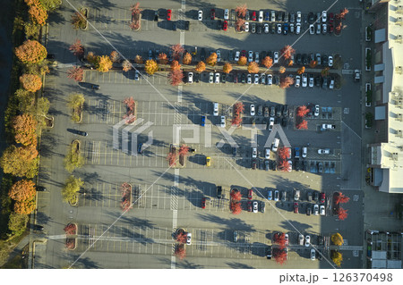 Aerial view grocery shopping mall and many colorful cars parked on parking lot with lines and markings for parking places and directions. Place for vehicles in front of a strip mall plaza Aerial view grocery shopping mall and many colorful cars parked on parking lot with lines and markings for parking places and directions. Place for vehicles in front of a strip mall plaza 126370498