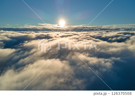 Aerial view from above at high altitude of dense puffy cumulus clouds flying in evening. Amazing sunset from airplane window point of view 126370508