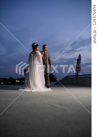 Young beautiful couple of newlywed posing in the evening against the background of an atmospheric panorama and stunning sunset Young beautiful couple of newlywed posing in the evening against the background of an atmospheric panorama and stunning sunset 126370959