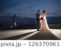 Young beautiful couple of newlywed posing in the evening against the background of an atmospheric panorama and stunning sunset 126370961