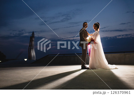Young beautiful couple of newlywed posing in the evening against the background of an atmospheric panorama and stunning sunset 126370961