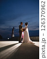 Young beautiful couple of newlywed posing in the evening against the background of an atmospheric panorama and stunning sunset 126370962