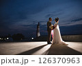 Young beautiful couple of newlywed posing in the evening against the background of an atmospheric panorama and stunning sunset 126370963