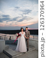 Young beautiful couple of newlywed posing in the evening against the background of an atmospheric panorama and stunning sunset 126370964