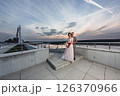 Young beautiful couple of newlywed posing in the evening against the background of an atmospheric panorama and stunning sunset 126370966