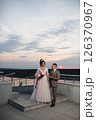 Young beautiful couple of newlywed posing in the evening against the background of an atmospheric panorama and stunning sunset 126370967
