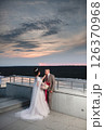 Young beautiful couple of newlywed posing in the evening against the background of an atmospheric panorama and stunning sunset 126370968