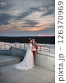 Young beautiful couple of newlywed posing in the evening against the background of an atmospheric panorama and stunning sunset 126370969