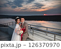 Young beautiful couple of newlywed posing in the evening against the background of an atmospheric panorama and stunning sunset 126370970