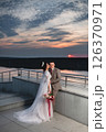 Young beautiful couple of newlywed posing in the evening against the background of an atmospheric panorama and stunning sunset 126370971