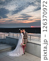Young beautiful couple of newlywed posing in the evening against the background of an atmospheric panorama and stunning sunset 126370972