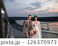 Young beautiful couple of newlywed posing in the evening against the background of an atmospheric panorama and stunning sunset 126370973