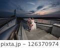 Young beautiful couple of newlywed posing in the evening against the background of an atmospheric panorama and stunning sunset 126370974