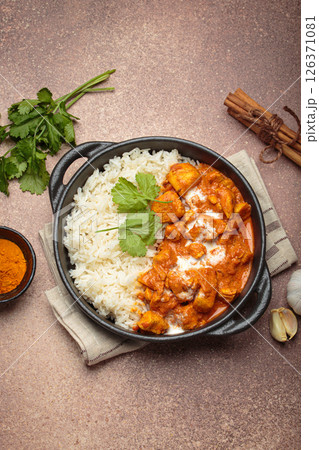 Indian dish chicken tikka masala served with rice and spices on beige background top view Indian dish chicken tikka masala served with rice and spices on beige background top view 126371081