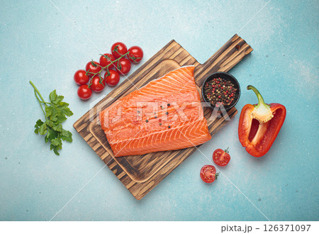 Fresh raw salmon fillet with cooking ingredients on wooden board top view on light blue background 126371097