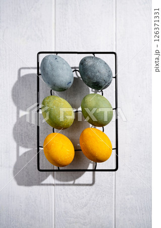 Easter eggs drying on a cooling rack after being naturally dyed with hibiscus and turmeric, creating a beautiful display of yellow and green hues, ready for easter celebration Easter eggs drying on a cooling rack after being naturally dyed with hibiscus and turmeric, creating a beautiful display of yellow and green hues, ready for easter celebration 126371331