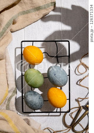 Easter eggs drying on a cooling rack after being naturally dyed with hibiscus and turmeric, creating a beautiful display of yellow and green hues, ready for easter celebration 126371334