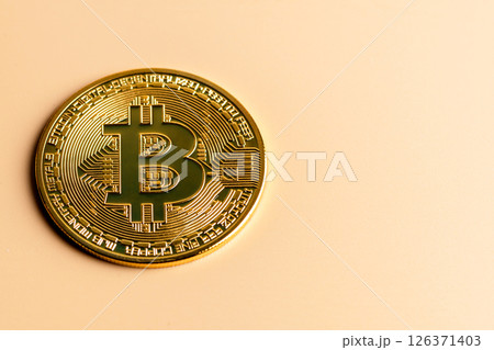 Physical golden bitcoin resting on a light brown surface, symbolizing cryptocurrency, investment opportunities, and the evolving landscape of digital finance and technology 126371403