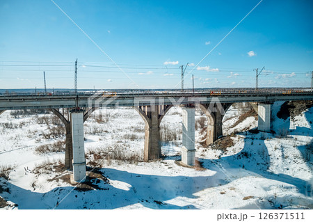 Long railway bridge stretching across a snowy landscape under a clear blue sky, highlighting transportation infrastructure amid a picturesque winter setting Long railway bridge stretching across a snowy landscape under a clear blue sky, highlighting transportation infrastructure amid a picturesque winter setting 126371511