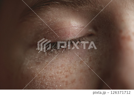 Extreme close-up of a closed eye with wet eyelashes and freckles, showcasing tiny droplets of water, creating a captivating image of beauty and vulnerability Extreme close-up of a closed eye with wet eyelashes and freckles, showcasing tiny droplets of water, creating a captivating image of beauty and vulnerability 126371712