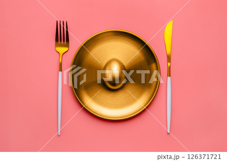 golden egg on golden plate a glistens alongside luxurious cutlery against a vibrant pink background, representing wealth, investment opportunities, and financial success 126371721