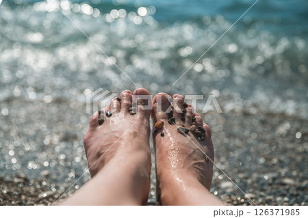 close up Female feet on the background of the sea surf, on the beach with small pebbles, concept vacation at the sea, relax 126371985