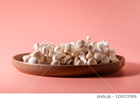 shimeji mushrooms on the plate, on pink, peach fuzz background 126372069