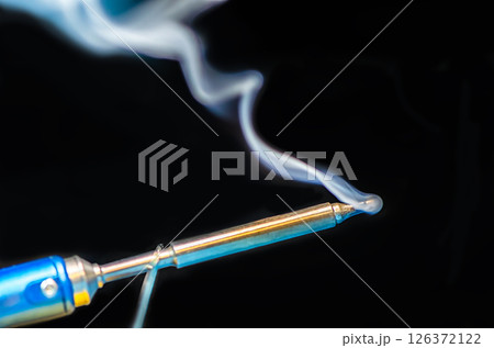 soldering iron with smoke on a black background. Electrical soldering iron with smoke on a black background. Electrical 126372122