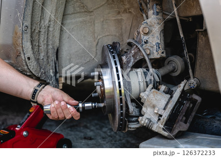 Mechanic man installing new brake disc and brake pads on car, car repair Mechanic man installing new brake disc and brake pads on car, car repair 126372233