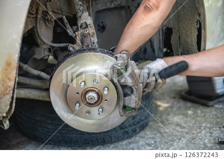 Mechanic man installing new brake disc and brake pads on car, car repair Mechanic man installing new brake disc and brake pads on car, car repair 126372243
