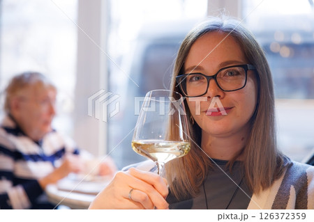 Celebrating cozy moments with friends over a glass of white wine in a stylish urban cafe Celebrating cozy moments with friends over a glass of white wine in a stylish urban cafe 126372359