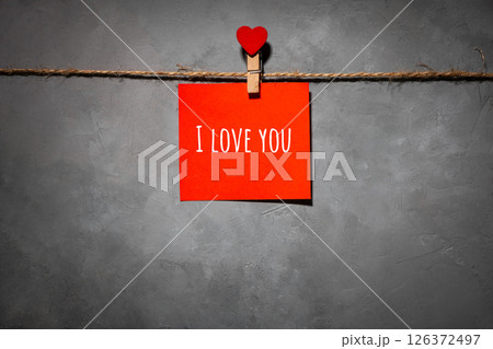 red paper with text I love you on a rope on a gray background. Background for a postcard red paper with text I love you on a rope on a gray background. Background for a postcard 126372497