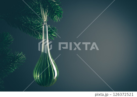 Elegant green christmas ornament hanging from a natural pine branch, creating a festive atmosphere against a dark background, perfect for holiday decorations and seasonal greetings 126372521