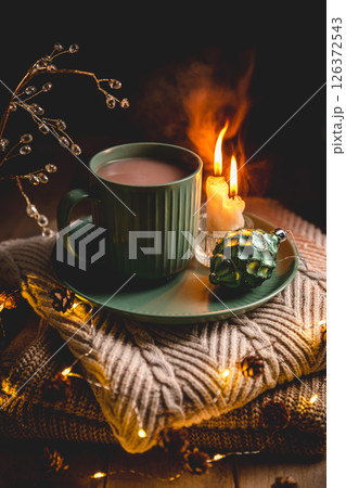 Christmas still life with mug of hot chocolate, candles and christmas lights on stack of knitted sweaters, creating cozy and festive atmosphere for christmas and new year celebrations, greeting card Christmas still life with mug of hot chocolate, candles and christmas lights on stack of knitted sweaters, creating cozy and festive atmosphere for christmas and new year celebrations, greeting card 126372543