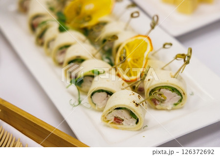 Savoring delightful chicken and vegetable rolls at a festive gathering in a cozy dining setting 126372692