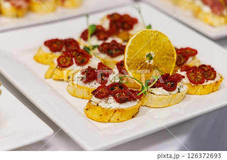 Delicious gourmet appetizers featuring sun-dried tomatoes and creamy cheese at a lively event 126372693