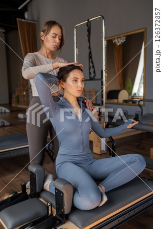 Woman training pilates on the reformer bed. Reformer pilates studio machine for fitness workouts in gym. Fit, healthy and strong authentical body. Fitness concept 126372857