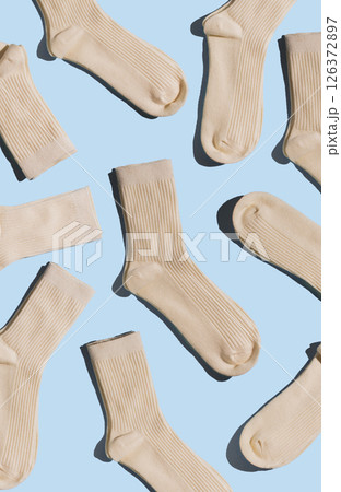 A variety of beige socks displayed on light blue background, highlighting textures and design in minimalism style, perfect for fashion and textile design projects. Vertical. 126372897