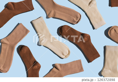 Colorful socks in shades of brown and beige are arranged on light blue background, highlighting their unique textures and patterns in visually appealing layout. Colorful socks in shades of brown and beige are arranged on light blue background, highlighting their unique textures and patterns in visually appealing layout. 126372898