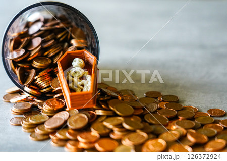 A Tiny Skeleton in a Coffin Lies Among Spilled Coins from a Jar, A Dark Symbol of Greed and Wealth 126372924