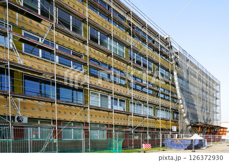 Renovation of office building covered in scaffolding and protective net during reconstruction work Renovation of office building covered in scaffolding and protective net during reconstruction work 126372930