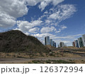Colorful High-Rises Beside a Bare Hill Under Clouded Sky 126372994