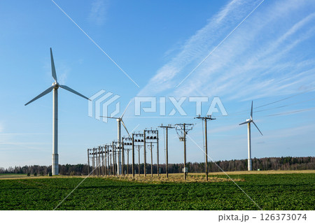 Wind Turbines and Power Lines in a Green Field Generating Clean Renewable Energy Under a Blue Sky 126373074